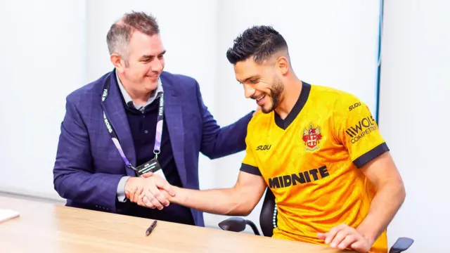 A photo of Raul Jimenez, wearing the new Wolverhampton Wanderers home kit, shaking the hand of Matt Wild as he signs a new contract with the club