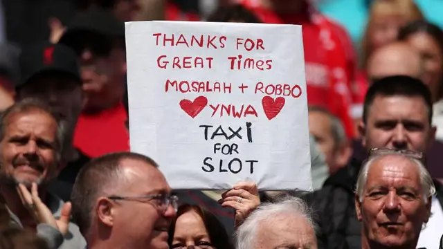 A fan of Liverpool holds up a sign which reads "Thanks for great times, mo.Salah + Robbo, YNWA, Taxi for slot" prior to the Premier League match between Liverpool and Chelsea at Anfield