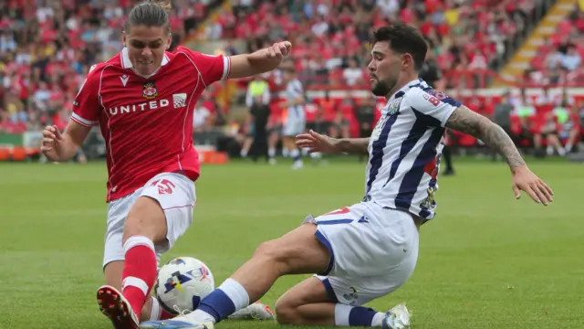 Wrexham midfielder George Dobson (L) challenges West Bromwich Albion's Alex Mowatt