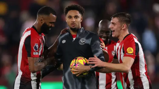 Kevin Schade of Brentford celebrates victory with teammates with his hat-trick match ball after the Premier League match between Brentford FC and Leicester City FC at Gtech Community Stadium