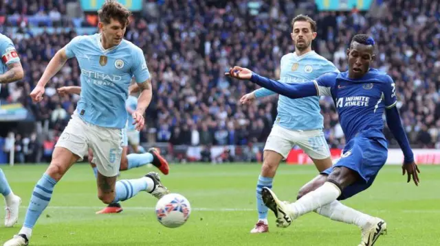 Nicolas Jackson of Chelsea shoots past John Stones of Manchester City
