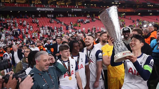Tottenham players celebrate with trophy in front of stands