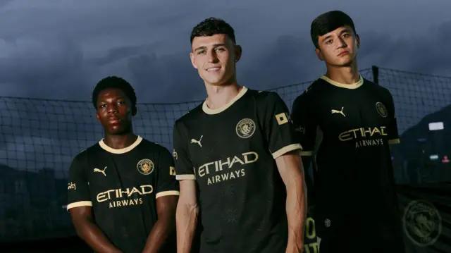 Phil Foden, Abdukodir Khusanov and Ryan McAidoo modelling Manchester City's new away kit
