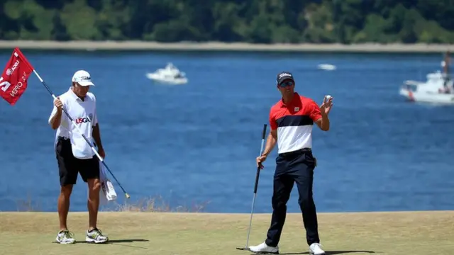 Adam Scott holds up his ball