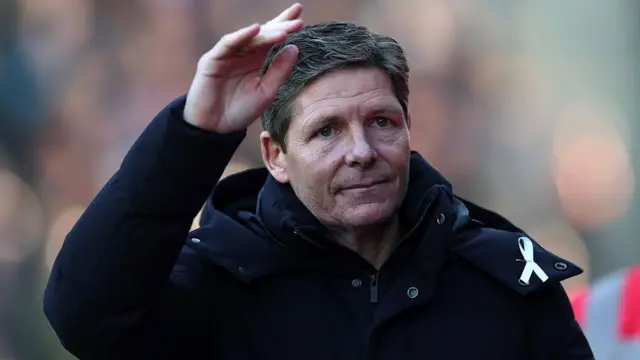 Oliver Glasner, wearing a dark coat and waving to the cowd