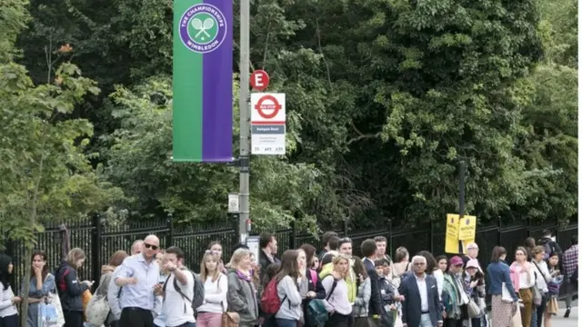 A long line of people waiting at a bus stop in Wimbledon, south west London, as tennis fans leaving the All England Club