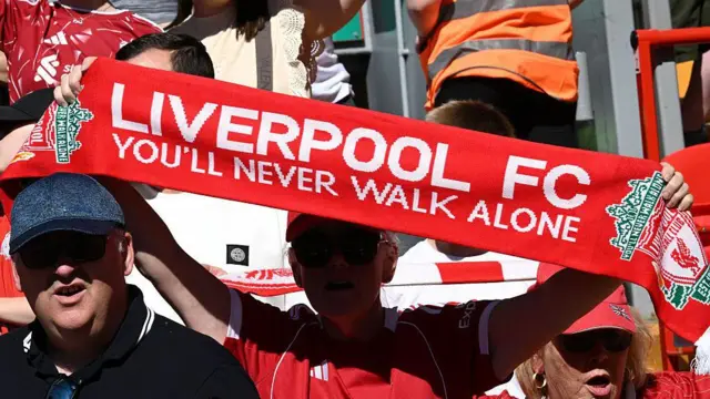 Liverpool fan holds up You'll Never Walk Alone scarf