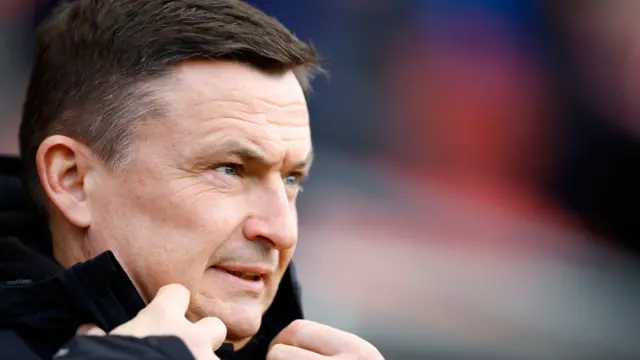 A side-on shot of Paul Heckingbottom as he is about to button up the top of his big coat