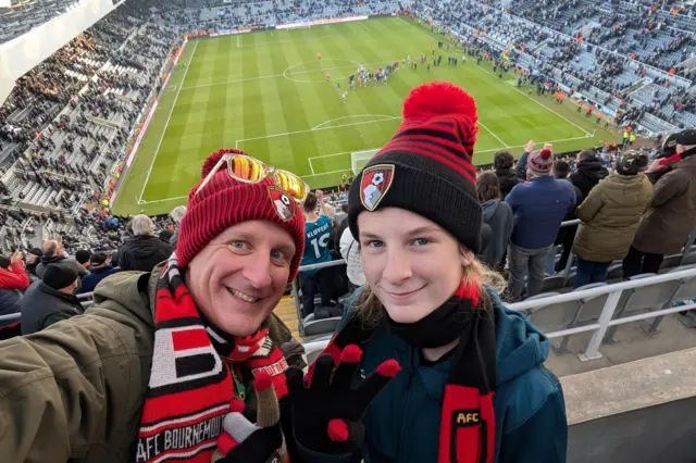Selfie of a dad and daughter in their Bournemouth hats and scarves up in the stands at St James' Park