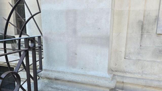 A stone wall stained with a faint cross.