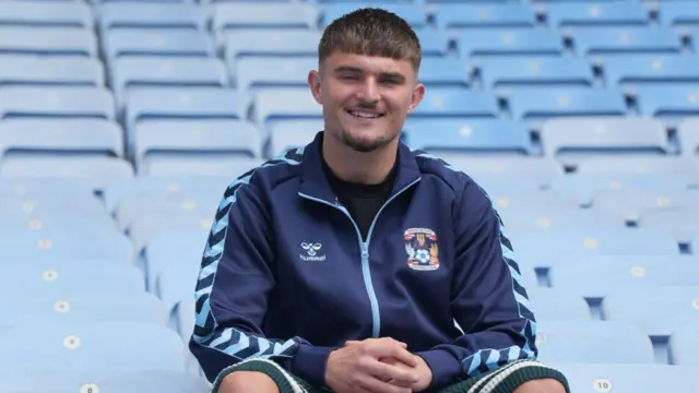 A smiling Callum Perry poses in the stands at Coventry Building Society Arena