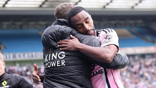 Leicester City head coach Gary Rowett, in a black coat with the King Power logo on the back, hugs player Andreas Pereira, in pink with black and white trim, at the final whistle against Blackburn Rovers.