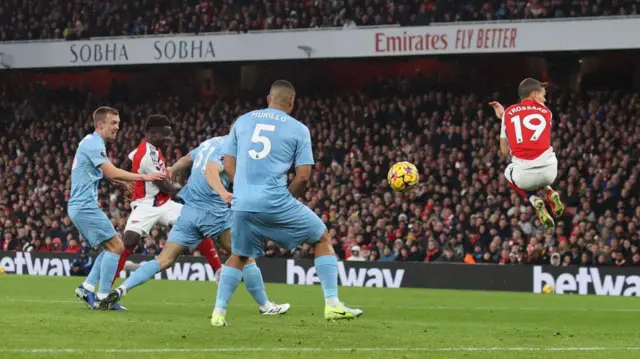 Leandro Trossard of Arsenal jumps out of the way as Bukayo Saka of Arsenal scores the opening goal