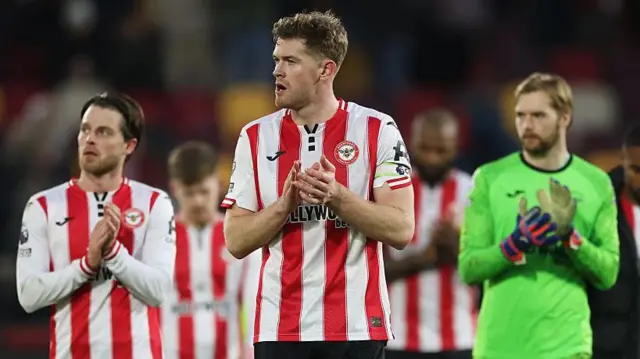 Nathan Collins claps his hands as he stands in front of Brentford team-mates