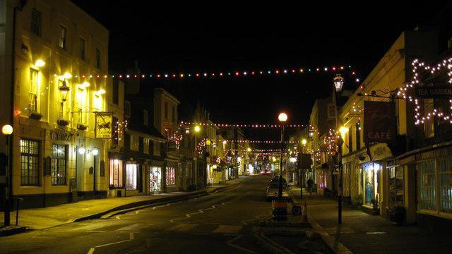 Battle High Street which has pubs and shops pictured in the dark with multicoloured christmas lights