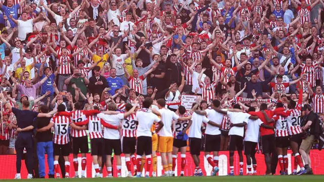 Sunderland fans celebrate as players stand in line with arms around each other's shoulders