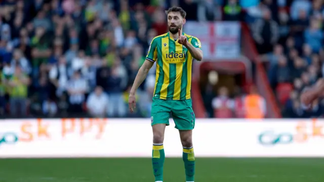 A photo of Nat Phillips pointing while playing football in his green and yellow striped West Bromwich Albion away kit
