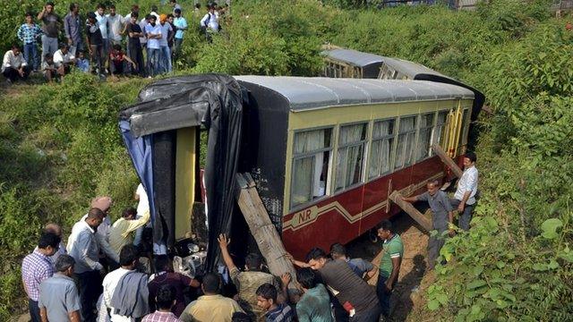 Men stand next to the derailed carriages of an Indian tourist train in Himachal Pradesh, India