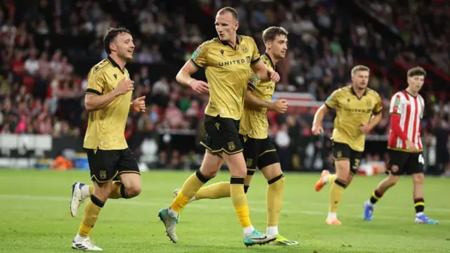 Ollie Rathbone and Will Boyle run back after celebrating Wrexham's opening goal at Sheffield United 