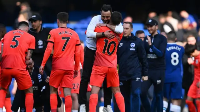 Roberto de Zerbi is lifted off his feet by Alexis Mac Allister