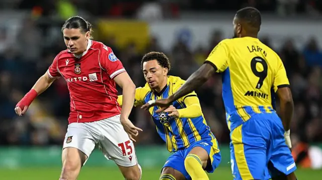 George Dobson of Wrexham is challenged by Samuel Edozie and Cyle Larin of Southampton during the clubs' meeting in April 
