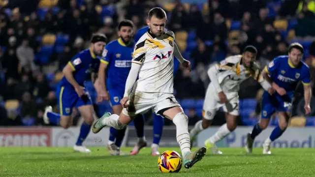 Shane McLoughlin takes a penalty for Newport in white change kit against Wimbledon 