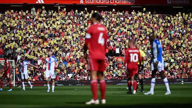 Liverpool fans hold up posters in protest.