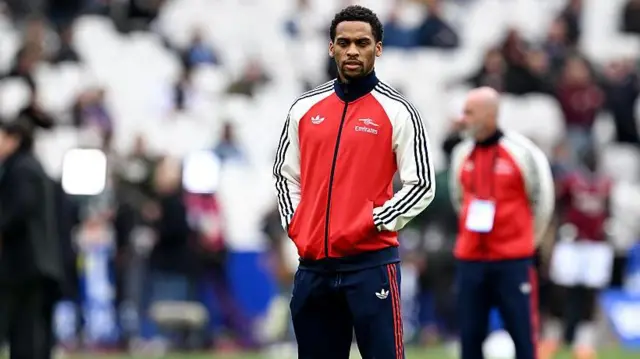Jurrien Timber standing on the pitch in an Arsenal tracksuit before their game against West Ham