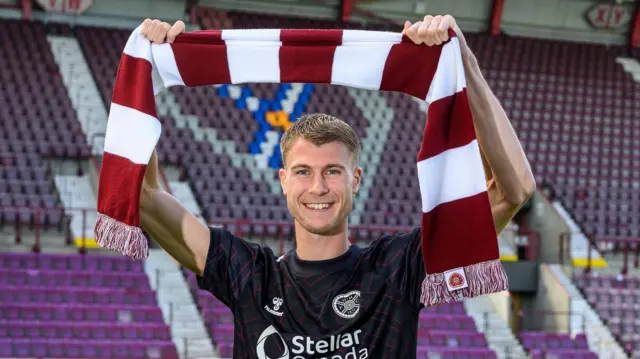 Hearts goalkeeper Beau Reus holds a scarf above his head at Tynecastle