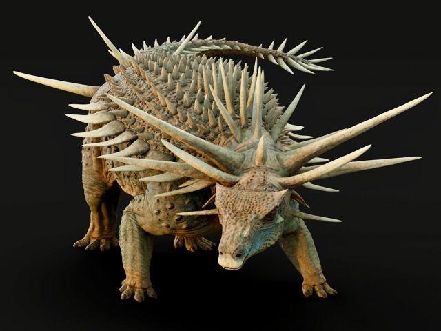The dinosaur has brown green skin against a black background. Its face is like a crocodile with prominent spikes coming out of its neck and the top of its head - with smaller spikes running down its back