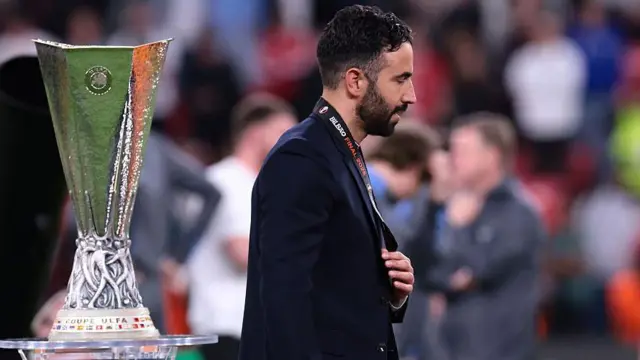 Ruben Amorim looks dejected as he walks past Europa League trophy