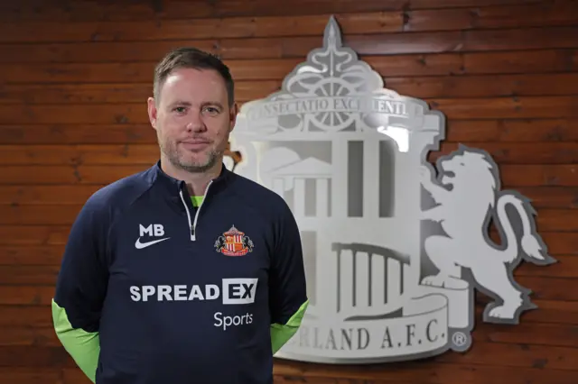 Michael Beale stood in front of the Sunderland logo