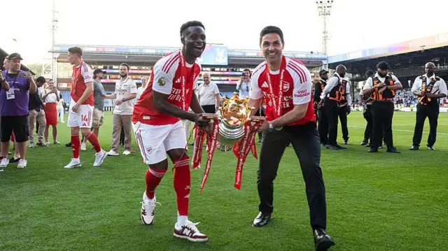 Bukayo Saka and Mikel Arteta celebrate with Premier League trophy