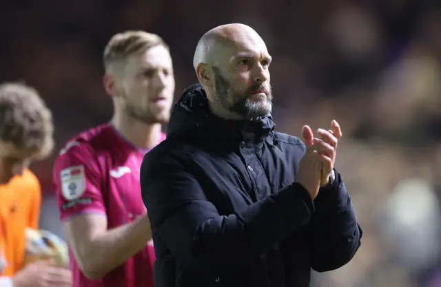 Luke Williams applauds supporters (out of frame) with Harry Darling wearing the Swansea City pink third shirt behind him 