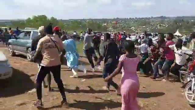 Daniel Uyirwoth Welo is seen wearing blue scrubs running through a crowd of people as they start to chase him at a cemetery in Bunia 