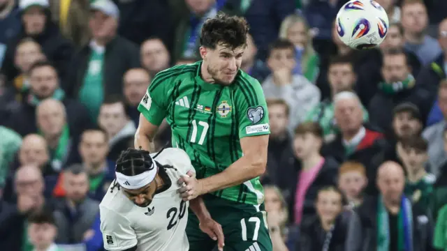 Paddy McNair heads the ball against Serge Gnabry