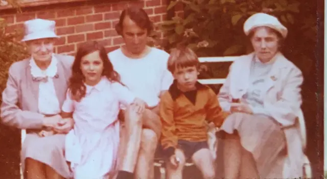 A picture of a family all dressed in white apart from a boy in a gold Wolves shirt and black shorts