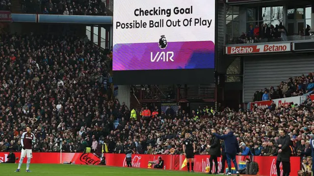 The big screen displays an ongoing VAR (Video Assistant Referee) review for a ball being out of play after Villa score