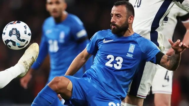  Manolis Siopis of Greece competes for the ball against England