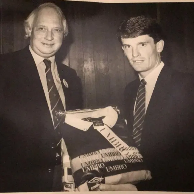 A black and white image of former Umbro chairman Stuart Humphreys presenting former Manchester City player Brian Marwood with a 'man of the match' award