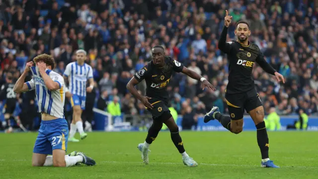 Wolves players celebrate a late goal against Brighton who look dejected