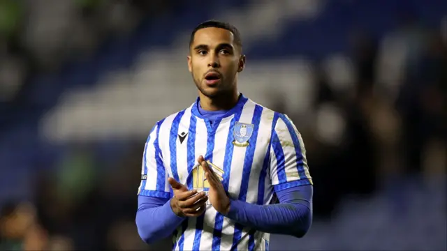 Defender Max Lowe wearing a blue and white striped Sheffield Wednesday shirt claps with a disappointed look on his face