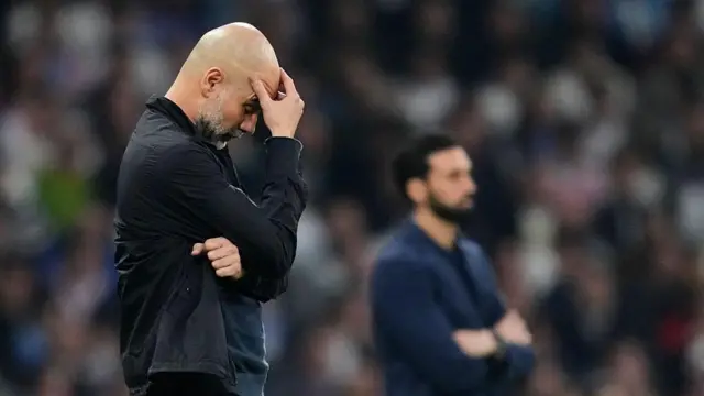 Pep Guardiola places his head on his hand. He looks despairing on the touchline.