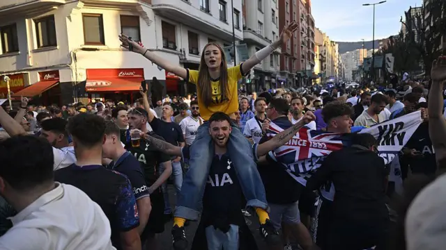 A female Tottenham fan on the shoulders of a male Tottenham fan
