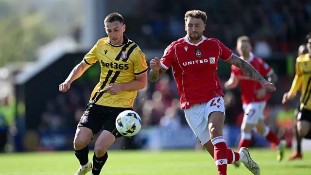Robert Bozeník of Stoke City is tackled by Dan Scarr of Wrexham during a match between Wrexham AFC and Stoke City at Stok Cae Ras