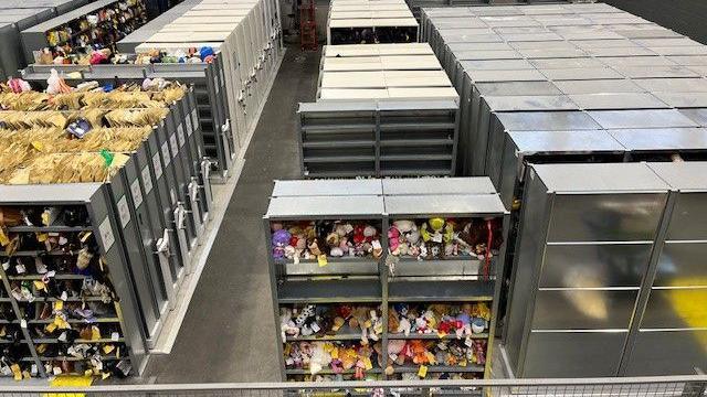 A large warehouse with large cabinets full of lost property, including cuddly toys, documents and other items which aren't completely visible