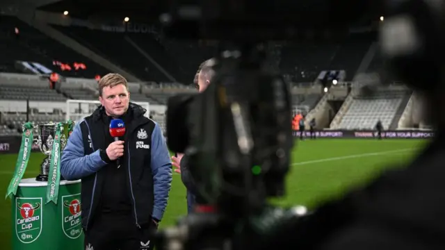 Eddie Howe gives a television interview next to the Carabao Cup