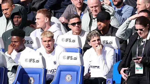 Enzo Fernandez sits behind Chelsea's bench in his normal clothes during defeat to Manchester City