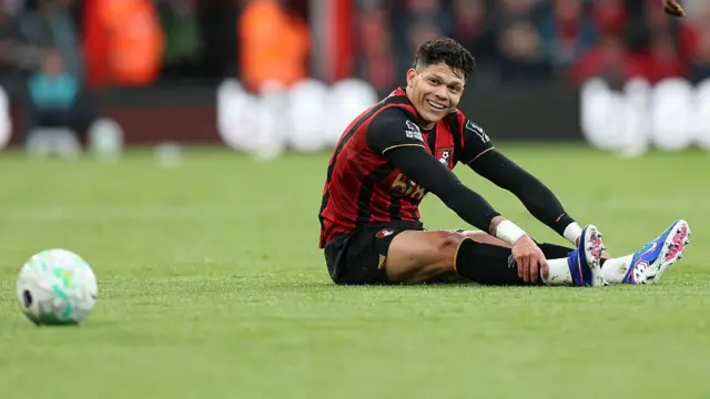 Evanilson sits on the turf and smiles
