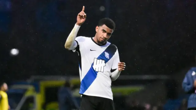 Jhon Solis holding finger up during a match while wearing a white Birmingham City shirt with a blue diagonal stripe